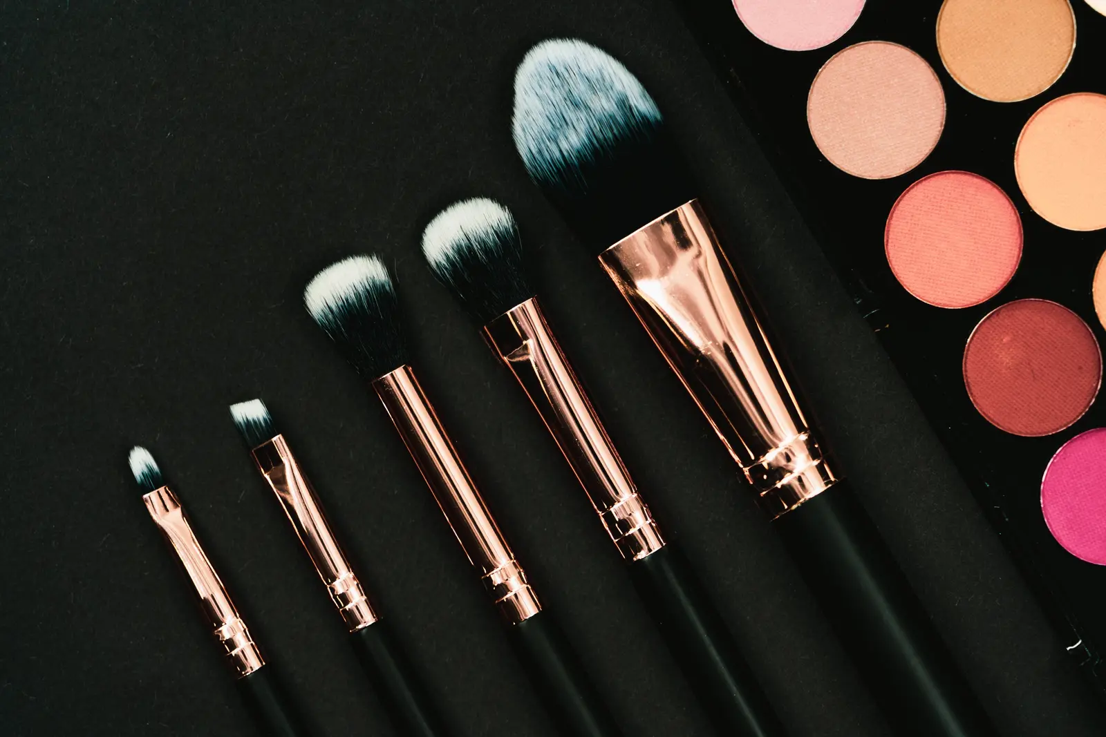 Makeup brushes and an eyeshadow palette on a dark surface