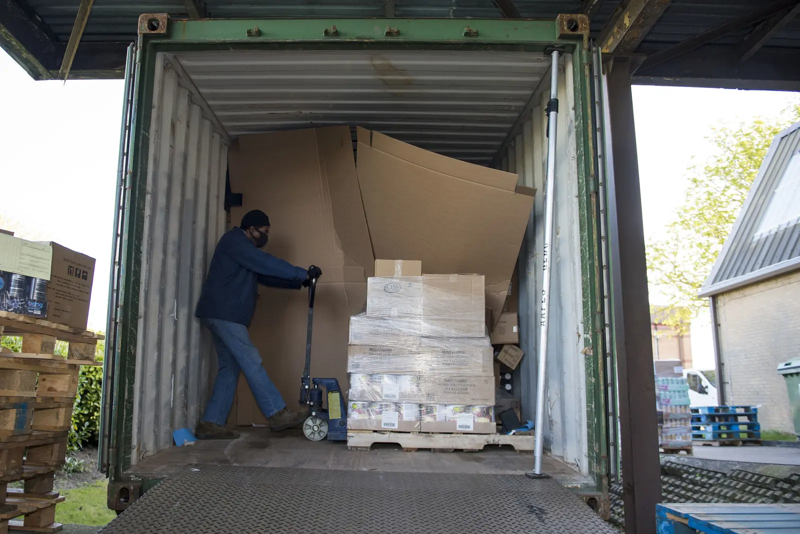 Worker unloading boxed goods from a shipping container onto pallets