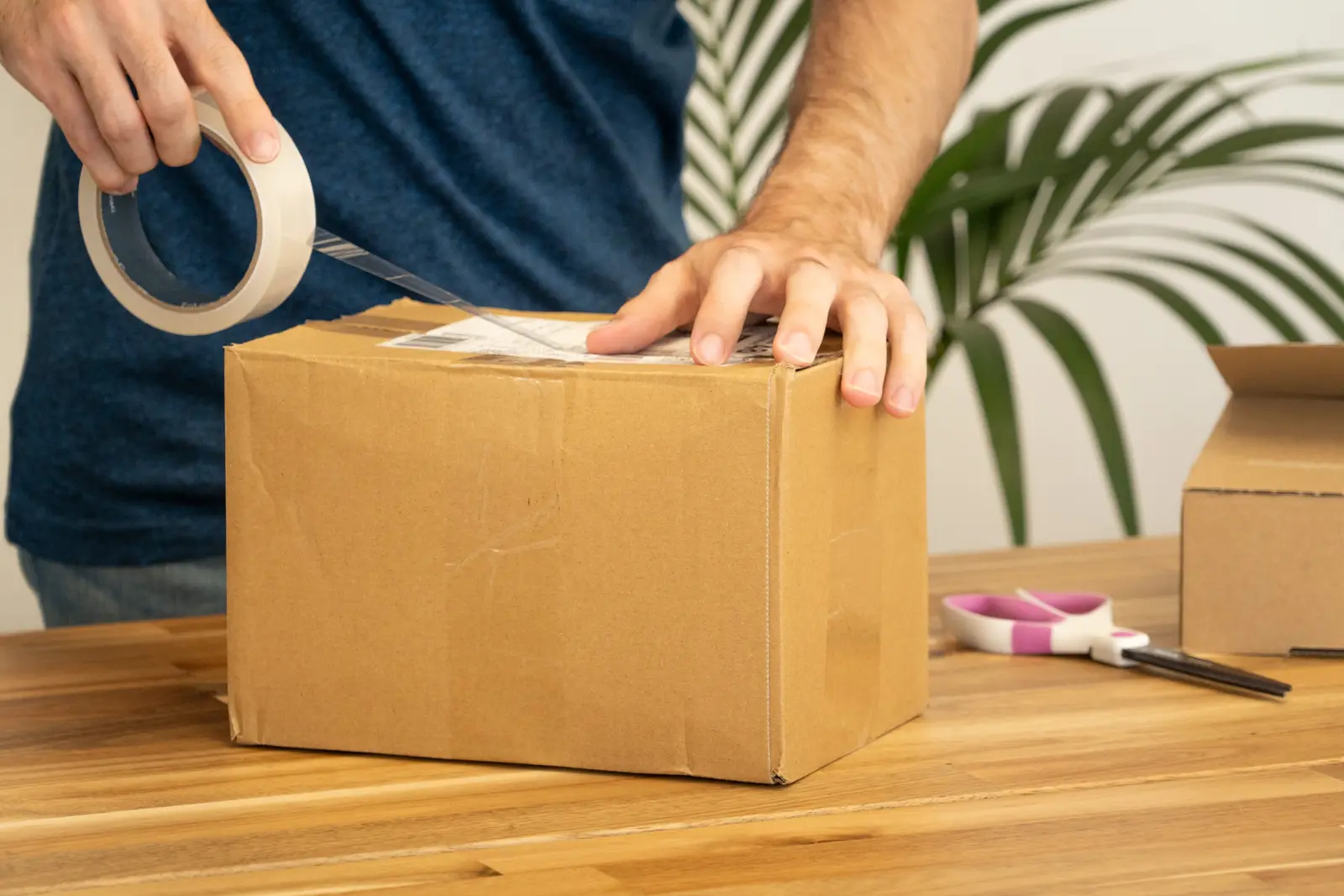 Hands applying a shipping label to a cardboard box