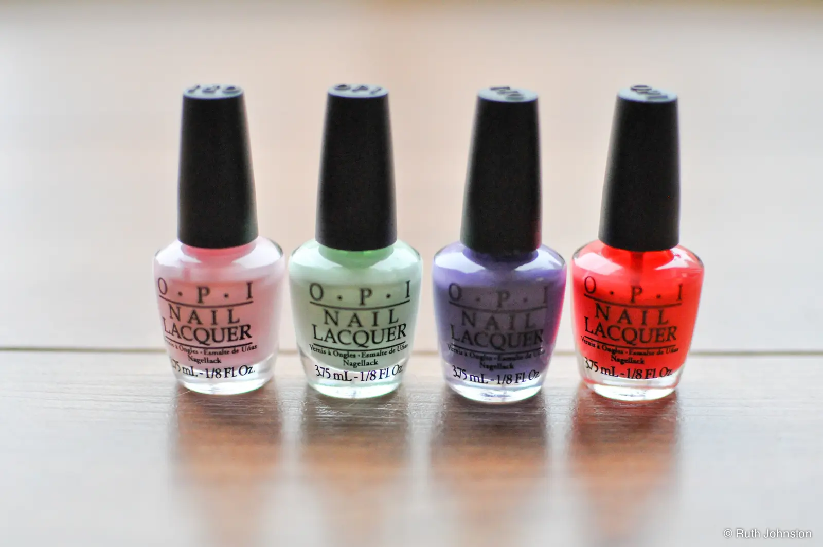 Four bottles of nail lacquer in pink, mint, lavender and red